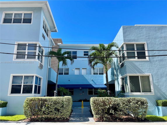 Front view of a multi-story building with light blue exterior and multiple windows.