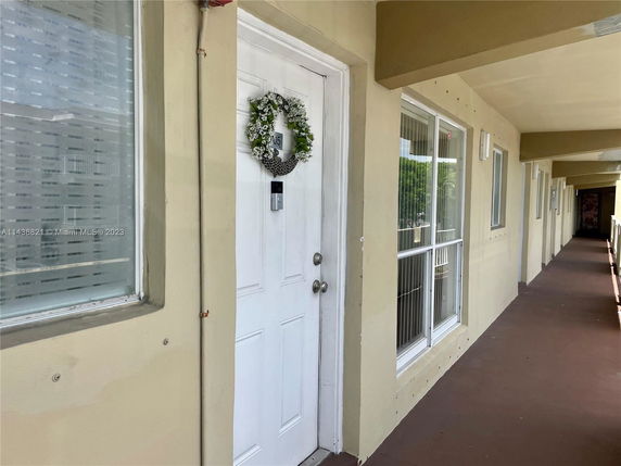Exterior walkway view of a building with white doors and windows.