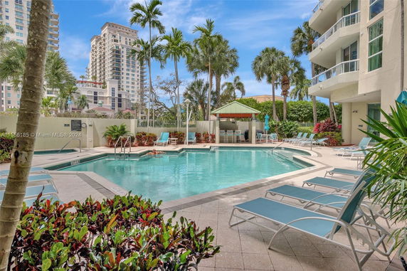 Outdoor swimming pool area with lounge chairs and a small bar structure.
