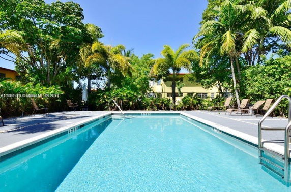 Outdoor view of a swimming pool surrounded by palm trees and lounge chairs.
