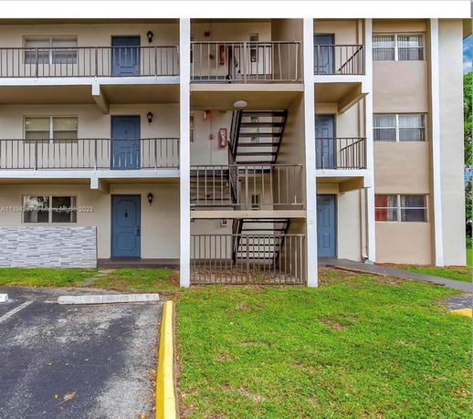 Front view of a multi-story apartment building with balconies and external staircases.