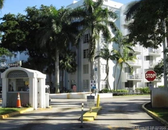Front view of a multi-story apartment building with surrounding palm trees.