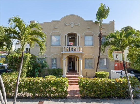 Front view of a two-story building with a decorative arch and balcony.