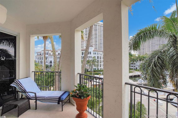 View from a balcony overlooking a resort-style area with palm trees and multi-story buildings.