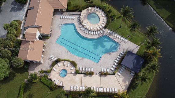 Aerial view of a large outdoor swimming pool area with surrounding lounge chairs.