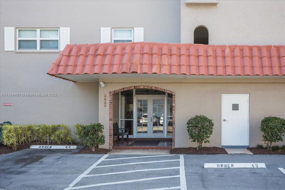 Front view of a building with a red-tiled roof and an arched entrance.