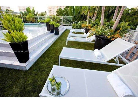 Rooftop with pool and lounge chairs surrounded by plants.