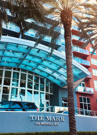 Front view of a modern multi-story building with a glass entrance and balconies.
