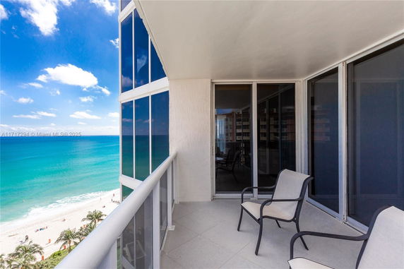 Balcony view from a building overlooking the ocean and beach.