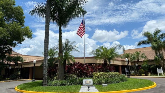Front view of a single-story building with an American flag and palm trees.