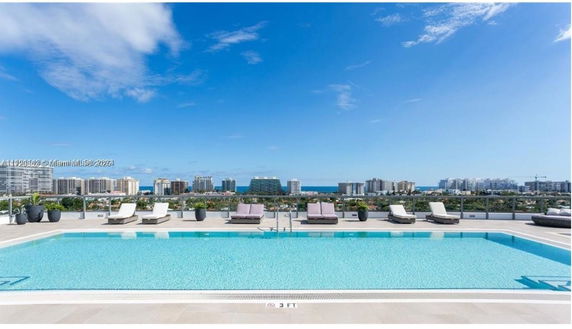 Rooftop swimming pool with lounge chairs and view of city skyline.
