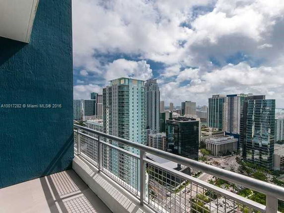 Panoramic view of a cityscape with tall buildings seen from a balcony.