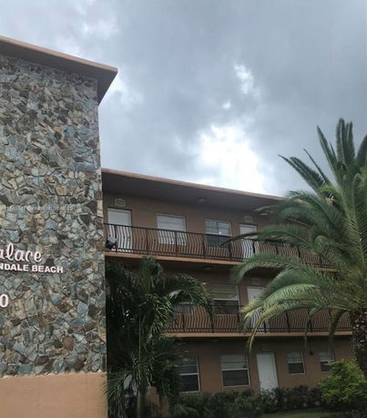 Front view of a multi-story building with stone exterior and balconies.