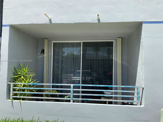 Front view of a house with a small balcony and sliding glass doors.