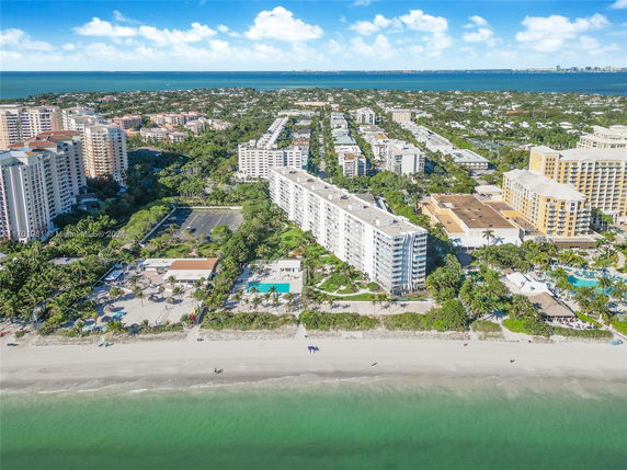 Aerial view of beachfront buildings with surrounding residential area and ocean.