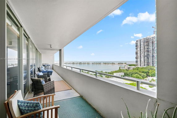 Balcony with outdoor seating offering a panoramic view of waterfront and buildings.