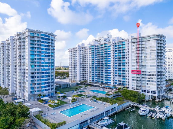 High-rise residential buildings near a waterfront with a swimming pool and boat docks.