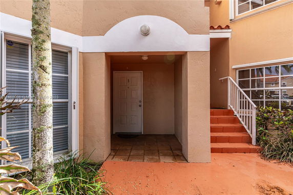 Entrance view of a building with a door under an archway and adjacent stairs.