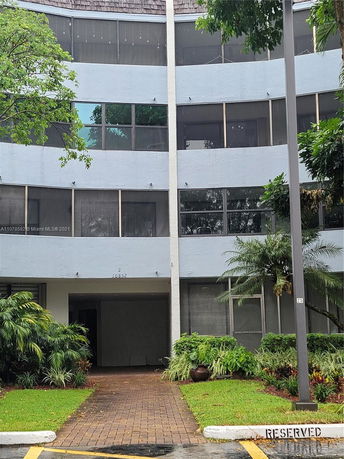 Front view of a multi-story building with large windows and a walkway leading to the entrance.