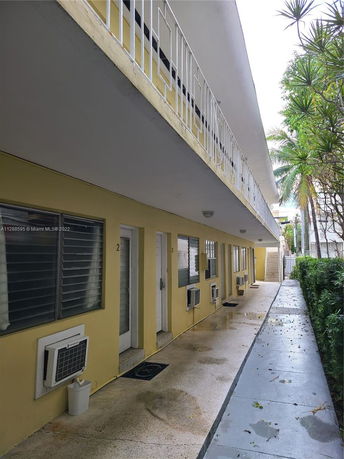 View of a two-story building with yellow exterior walls and multiple entry doors.