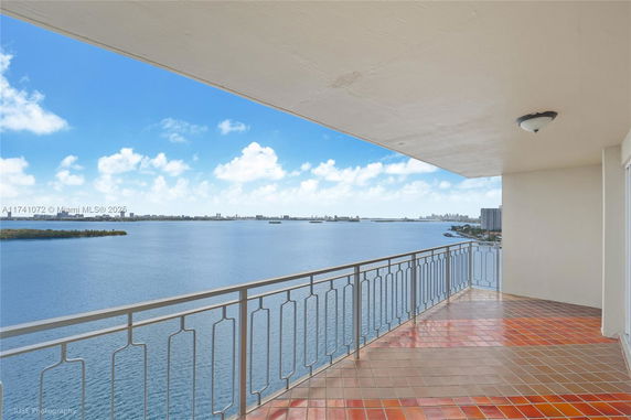 Panoramic view from a balcony overlooking a large body of water and distant city skyline.