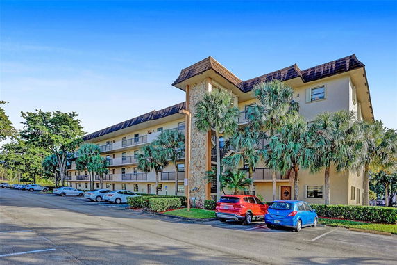 Front view of a multi-story residential building with balconies and parking area.