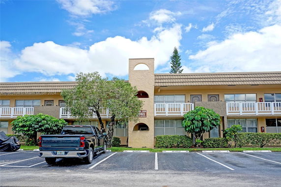 Front view of a two-story residential building with balconies and parking spaces.