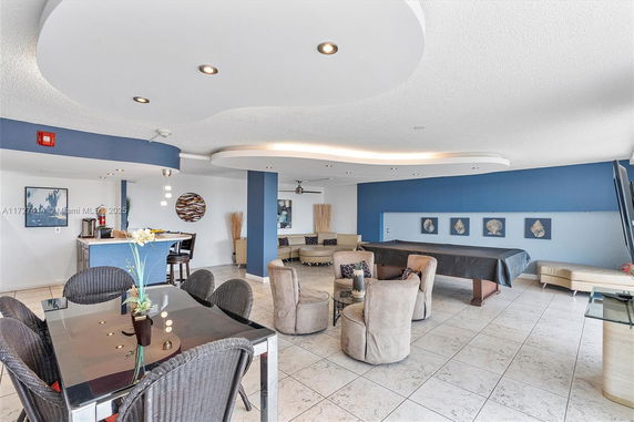 Room with a pool table, seating area, and dining table for recreational activities.