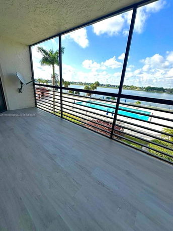 Panoramic view from a balcony overlooking a pool and a body of water.