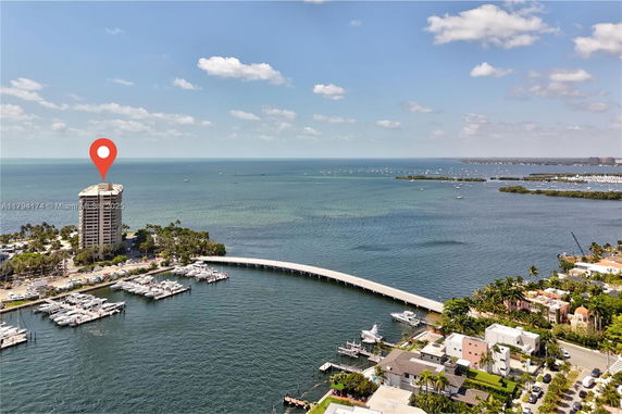 Panoramic view of a waterfront area with a high-rise building and marina.
