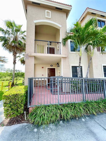 Front view of a two-story house with a balcony and entrance surrounded by railings.