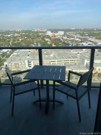 Panoramic view of a cityscape from a balcony with a small table and two chairs.