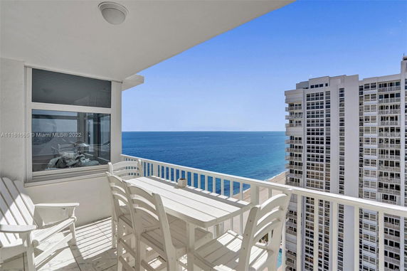 Balcony view overlooking the ocean and nearby high-rise buildings.