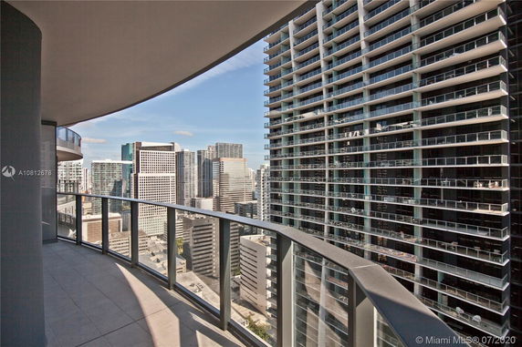 View from a building balcony overlooking city skyscrapers with glass balconies.