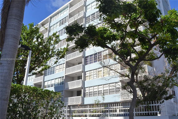 Front view of a multi-story apartment building with balconies and large windows.