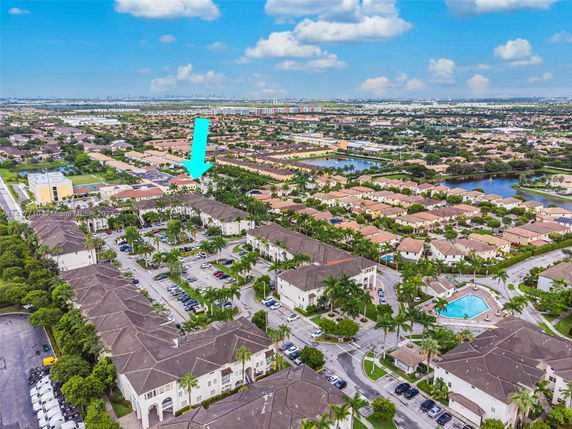 Wide-angle aerial view of a residential neighborhood with multiple houses, parking spaces, and a swimming pool.