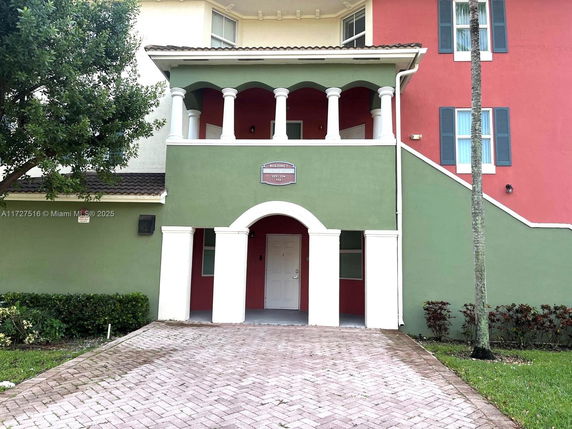Front view of a multi-story building with green and red exterior walls and arch design elements.