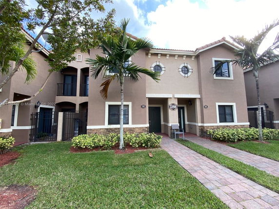 Front view of a two-story house with a landscaped entrance and arched windows.