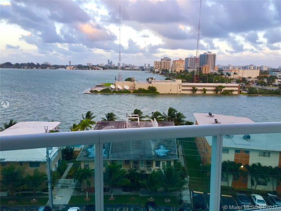 Panoramic view of a coastal cityscape with buildings, water, and cloudy sky.