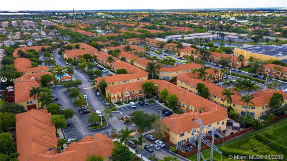 Aerial view of a large residential complex with orange roofs and surrounding greenery.