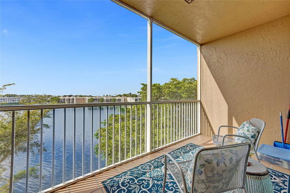 Screened balcony overlooking a body of water with distant buildings and trees.