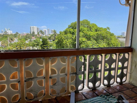 View of buildings and trees from a balcony with decorative railing.
