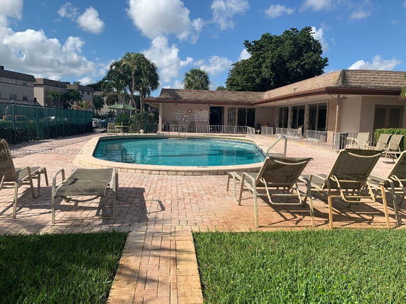 Outdoor swimming pool area with lounge chairs and surrounding building.