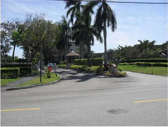 Front view of a large building with palm trees and a driveway.