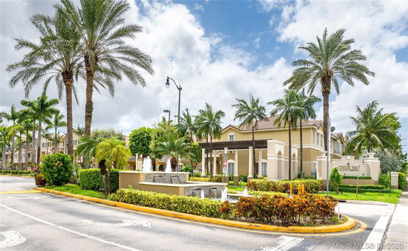 Front view of a residential building with palm trees and a water fountain.