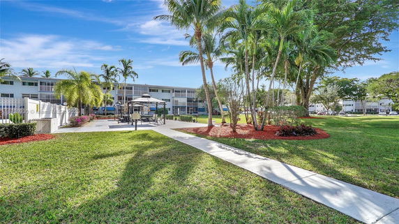 View of a residential complex surrounding a landscaped area with palm trees and pathways.