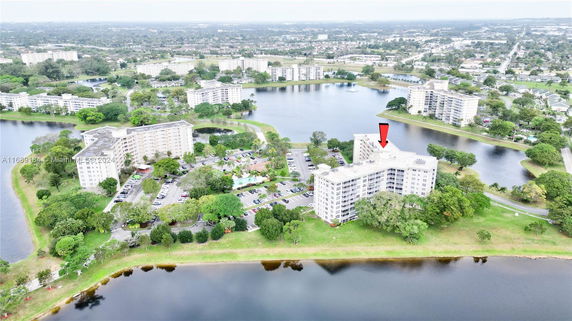Aerial view of a multi-story residential complex surrounded by water and greenery.