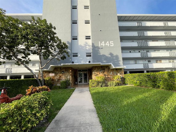 Front view of a multi-story residential building with a pathway leading to the entrance.