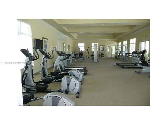 Interior view of a gym room with exercise equipment like treadmills and elliptical machines.