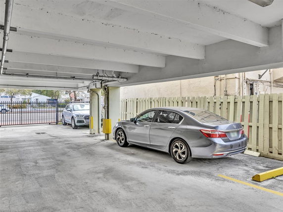 Covered parking area with multiple cars parked.